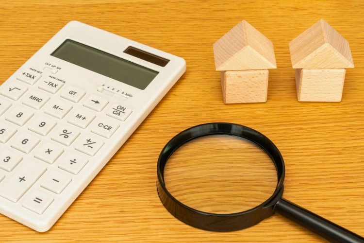 Calculatrice, loupe et maisons en bois pour représenter les fiscalités et impositions d'un marchant de biens
