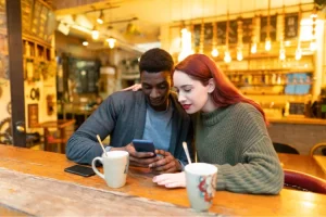 Couple dans un bar faisant une recherche d'image inversée sur un smartphone